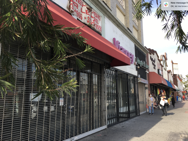 A storefront covered by metal gates with a "for lease" sign at the top.