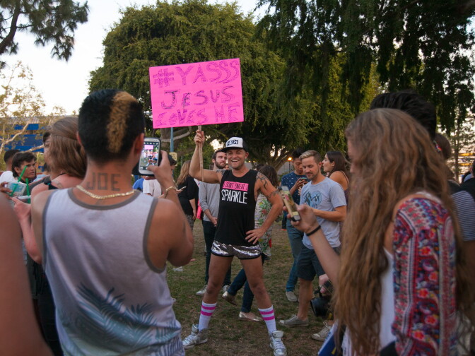 Onlookers line up to take photos with a man's humorous handmade sign during the Decision Day Rally in West Hollywood Park to celebrate the U.S Supreme Court decision on marriage equality on Friday, June 26, 2015.