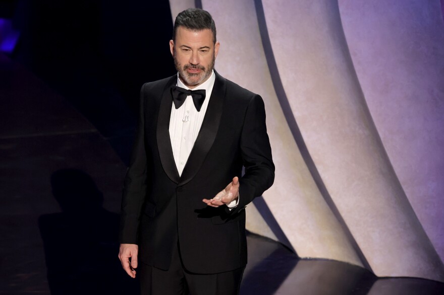 Jimmy Kimmel wears a traditional tux on a stage.