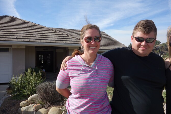Paula Howell and her son Paul Winbury outside their surviving home in Clearpoint, a neighborhood in Ventura. Nearby homes burned in the Thomas Fire.