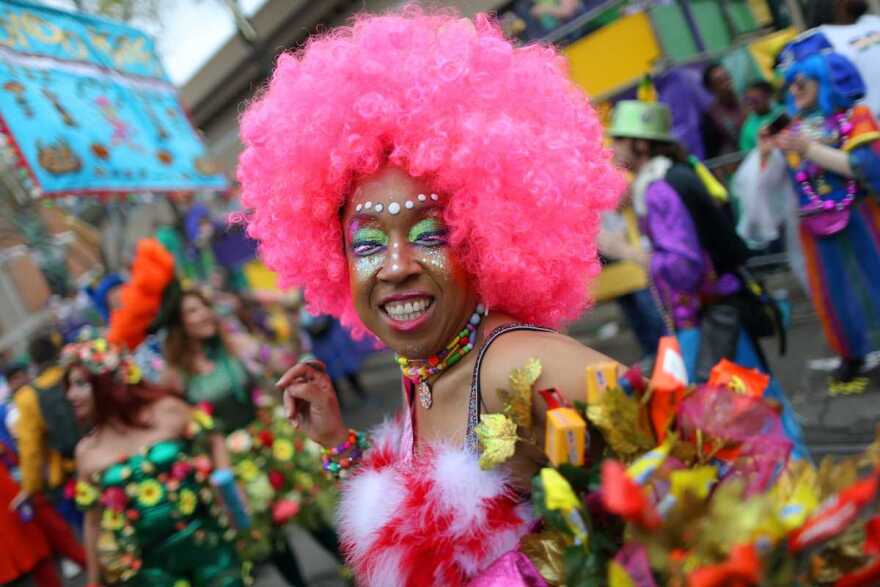 A reveleler in New Orleans dons a colorful pink wig and makeup during a Mardi Gras celebration.