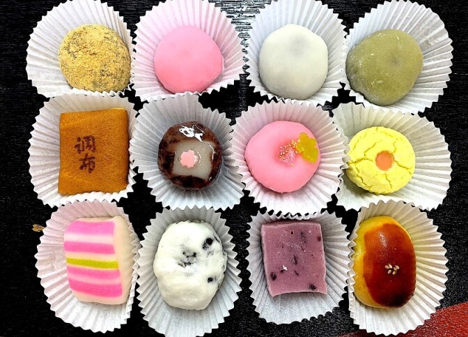 An assortment of colorful mochi in white paper wrappings. 