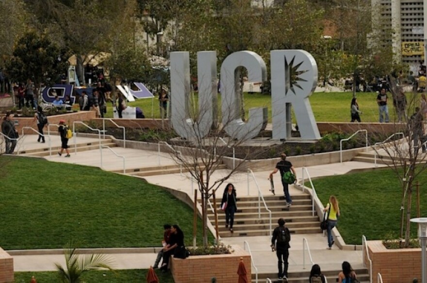 A large UCR cutout statue with students walking up and down the stairs in front of the plaza where it stands.