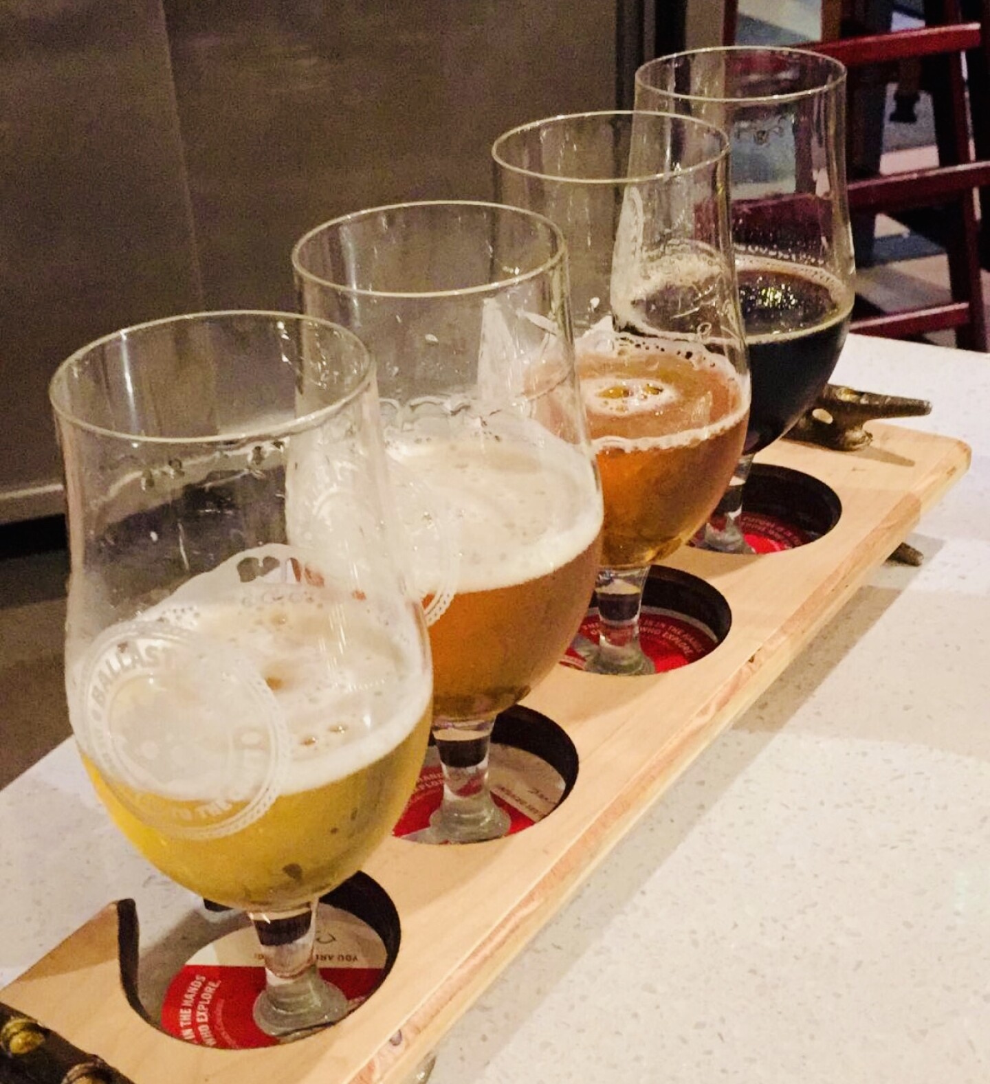 Four small glasses are filled with different kinds of beer.