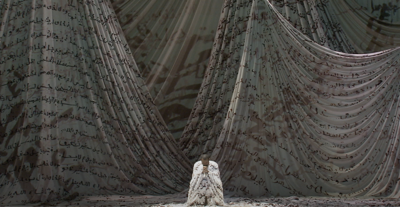 رجل راكع ويداه في الصلاة محاط بقطعة قماش ضخمة مكتوب عليها كلمات عربية