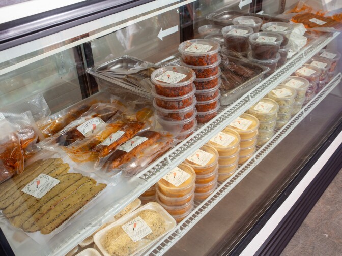 Containers of food are stacked in a display fridge