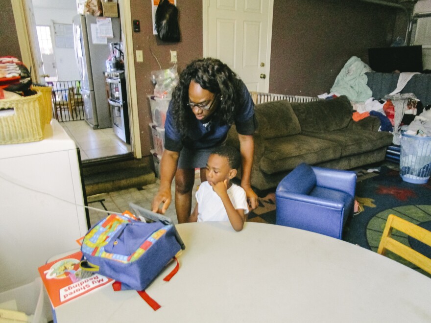In this image, a teacher helps a child with something on their tablet.