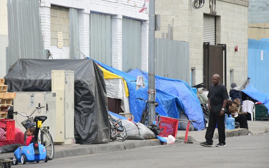 A man walks beside a row of tents for the homeless in Los Angeles, California on May 12, 2015.