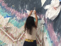 Craft in America education coordinator Brenda Cruz helps hang up flowers made by Clinton Middle School students. 