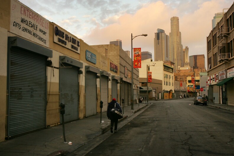 A homeless man walks down the street as a new day begins in the Wall Street area where the homeless have waken up before dawn to dismantle their beds and encampments before businesses open October 12, 2007 in the downtown Skid Row area of Los Angeles, California.