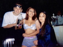 Three young people stand next to each other, the male presenting person wears a white t-shirt. The two female presenting people have long, dark hair.
