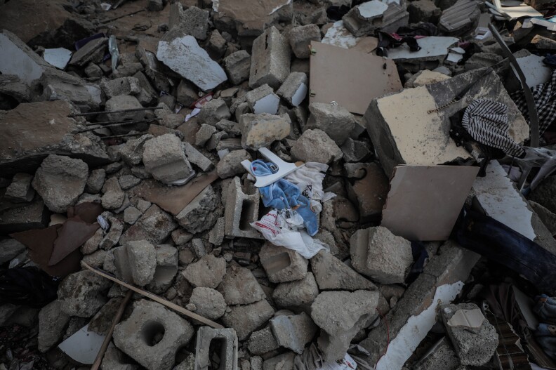 Children's clothes sit amid broken up blocks rocks and bricks.