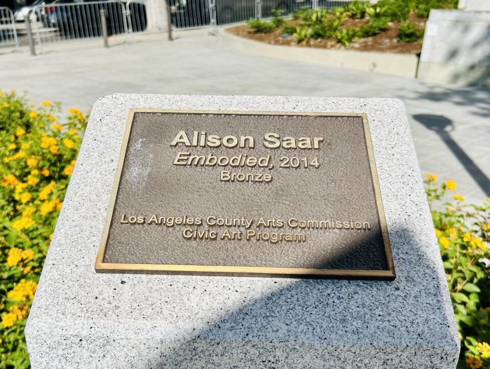 A bronze plaque with flowers around it.