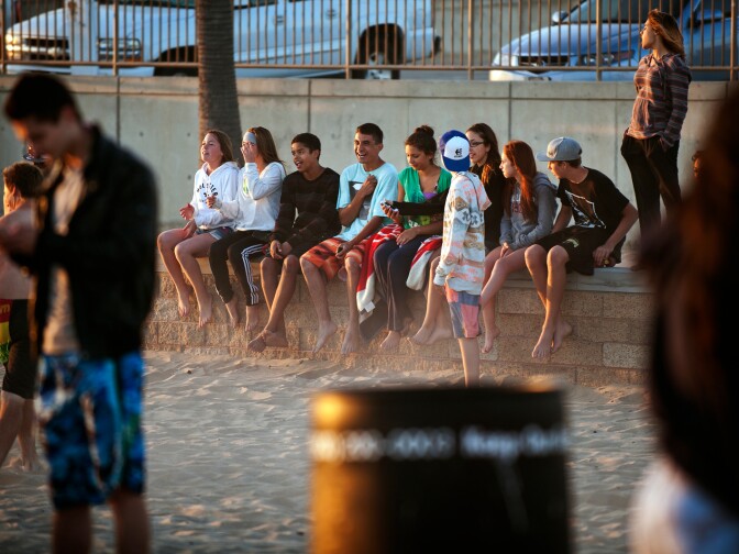 High school friends pose for a group picture at the Huntington Beach fire pits on Thursday evening, June 6. The South Coast Air Quality Management District says the fires release emissions that are harmful to the environment.