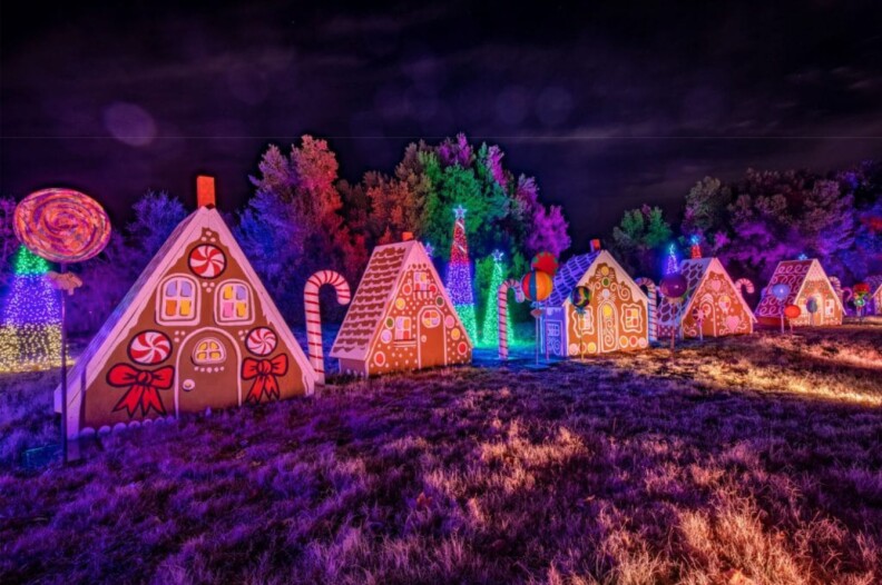 Large, decorated gingerbread houses in a row, separated by giant candy canes.