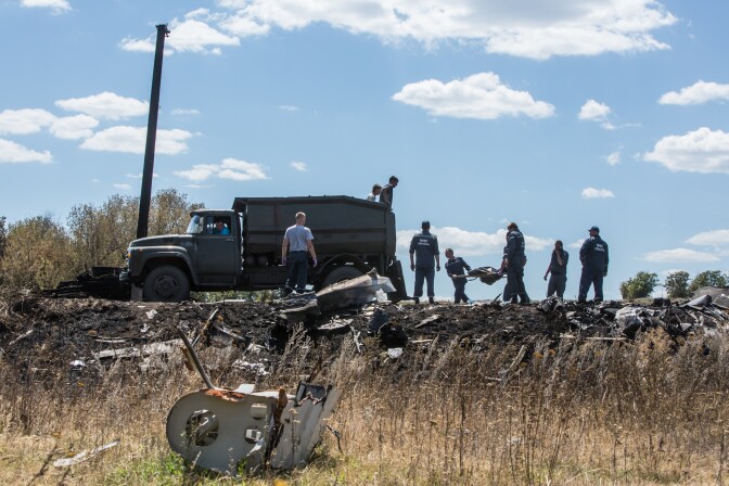 GRABOVO, UKRAINE - JULY 21: Personnel from the Ukrainian Emergencies Ministry load the bodies of victims of Malaysia Airlines flight MH17 into a truck at the crash site on July 21, 2014 in Grabovo, Ukraine. Malaysia Airlines flight MH17 was travelling from Amsterdam to Kuala Lumpur when it crashed killing all 298 on board including 80 children. The aircraft was allegedly shot down by a missile and investigations continue over the perpetrators of the attack. (Photo by Brendan Hoffman/Getty Images)