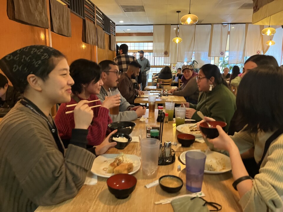 A table of six Asian American, Latino and white diners eat at a Japanese restaurant. 