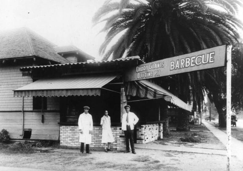 A group stands outside Daddy Grants Old Time Pit Barbecue restaurant on Washington Boulevard.