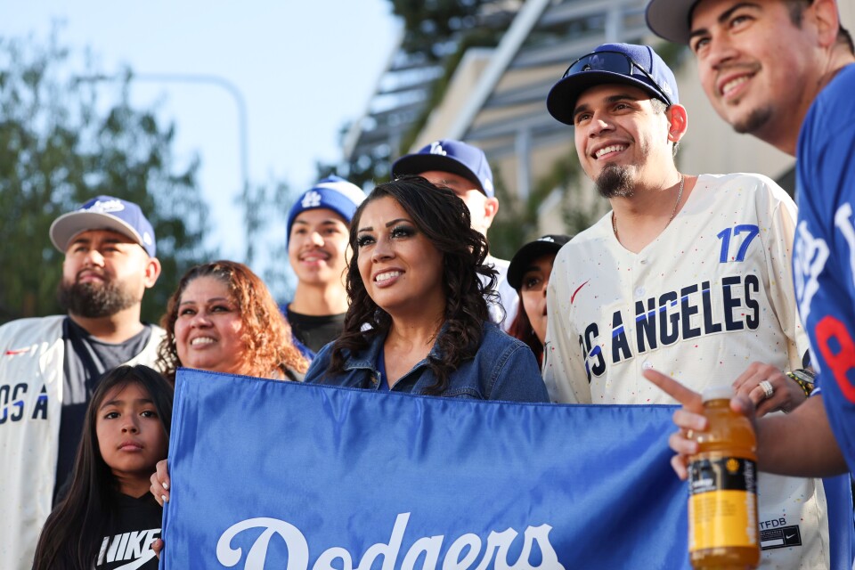 A woman holds up a blue banner that says "Dodgers" as others gather around her.