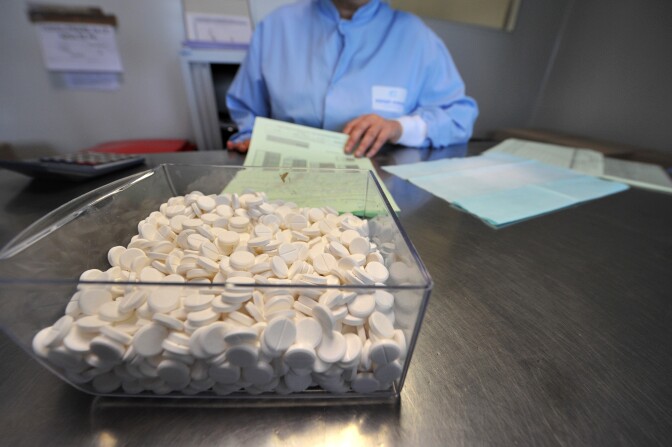 A person looks at documents next to a box filled with pills, on October 28, 2009 at French pharmaceutical group Sanofi-Aventis site in Lisieux, northern France. The site, created in 1982, is dedicated to the production of medicine containing paracetamol such as French brand name Doliprane, an over-the-counter drug. AFP PHOTO MYCHELE DANIAU (Photo credit should read MYCHELE DANIAU/AFP/Getty Images)