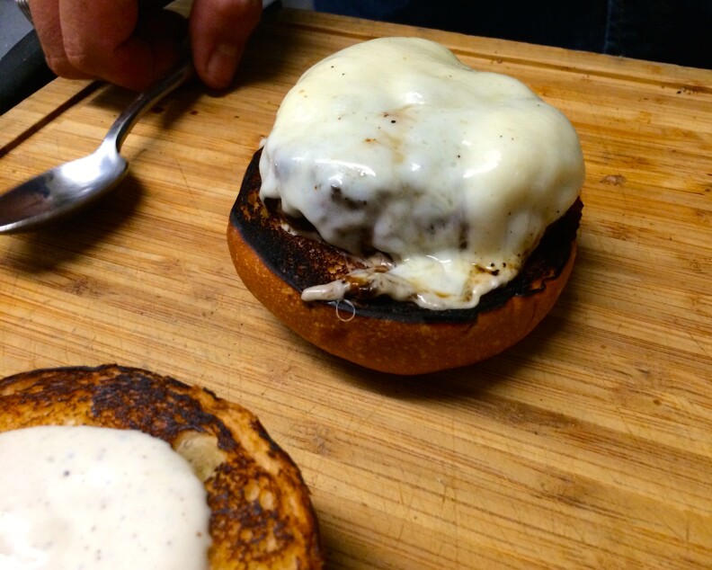 The beginnings of a truffle burger: a medium-rare patty cooked with muenster cheese.