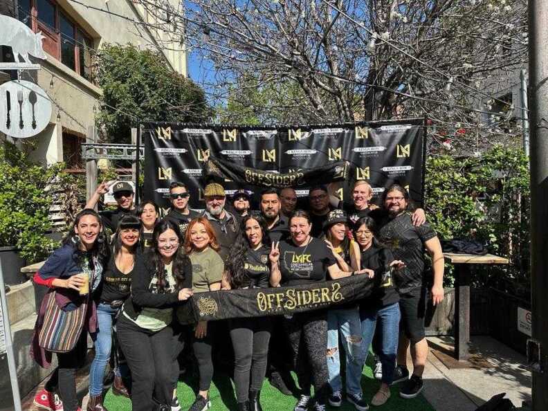 A group of men and women holding a banner that says "Offsiders" and posing for the camera.