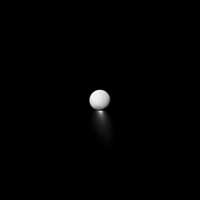 Saturn's moon Enceladus, and its plume of water, lit by sunlight reflecting off of the ringed planet.