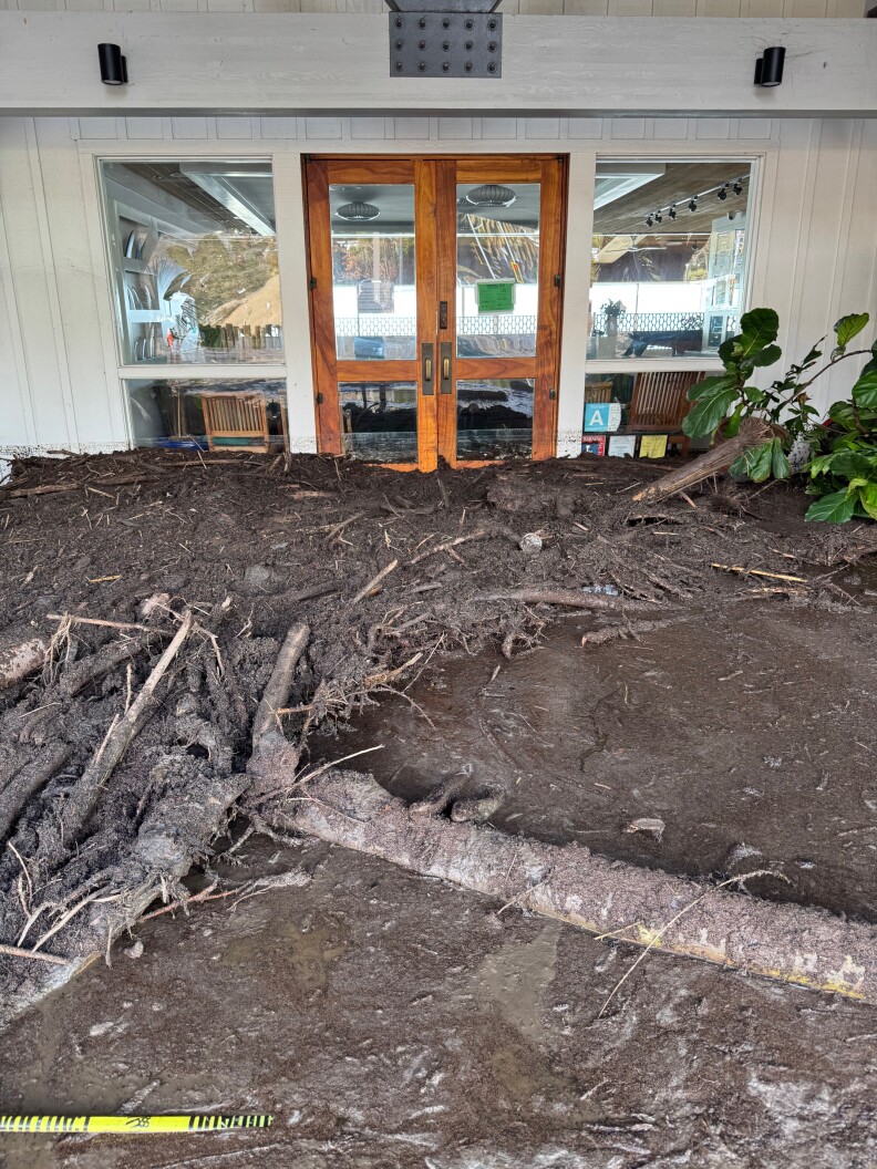 Mud and debris inundates the entrance to Duke's, covering part of the doors and windows.
