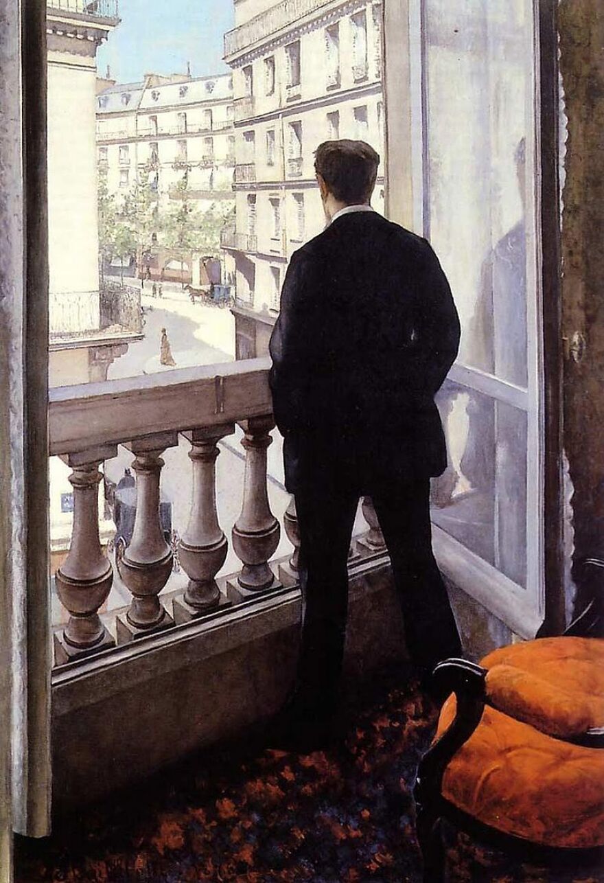 "Young Man at His Window." It shows a man in a black suit facing a window overlooking the town in a vividly realistic painting, with an orange armchair behind him, his reflection in the glass, carriages and a smattering of people in the street below.