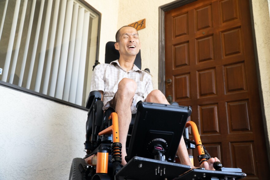 Tim Jin in his wheelchair in front of the door to his apartment in Orange County.