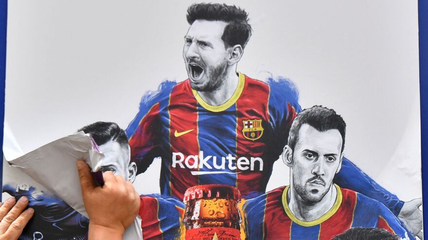A worker removes posters featuring FC Barcelona's departing Argentinian star Lionel Messi on Tuesday. Messi is poised to join Paris Saint-Germain.