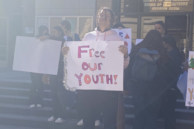 Floyd Lee Hardge stands outside the Board of Supervisors meeting holding a sign that reads "Free Our Youth!" 