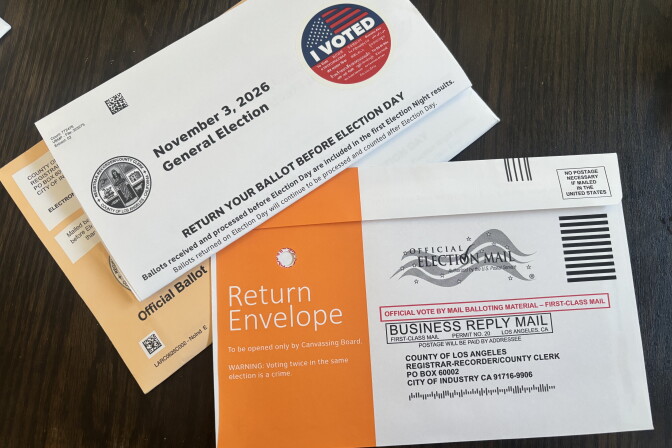 A Los Angeles County ballot envelope with an 'I Voted' sticker lies next to an orange return envelope for mail-in voting.