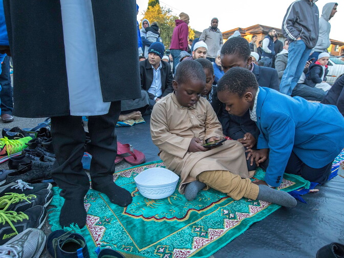 SYDNEY, AUSTRALIA - JUNE 25:  Children amuse themselves on aan iphone while waiting for the  prayers to coomence as crowds spill into the street and neighbouring houses and gardens for the traditional prayers of thanks during the  Eid al-Fitr end of Ramadan celebration. Worshipers flock to the Lakemba Mosque in suburban Sydney, Australia. . The religious Eid al-Fitr festival is celebrated for three days the end of the holiest month of Ramadan, where Muslims fast from sunrise to sunset for a month.  June 25, 2017  (Photo by Michele Mossop/Getty Images)
