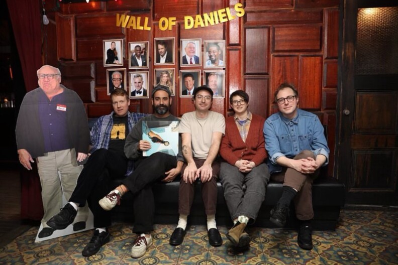 The band members of 'Real Estate' sit on a couch together holding their new album next to cut out of actor Danny Devito.