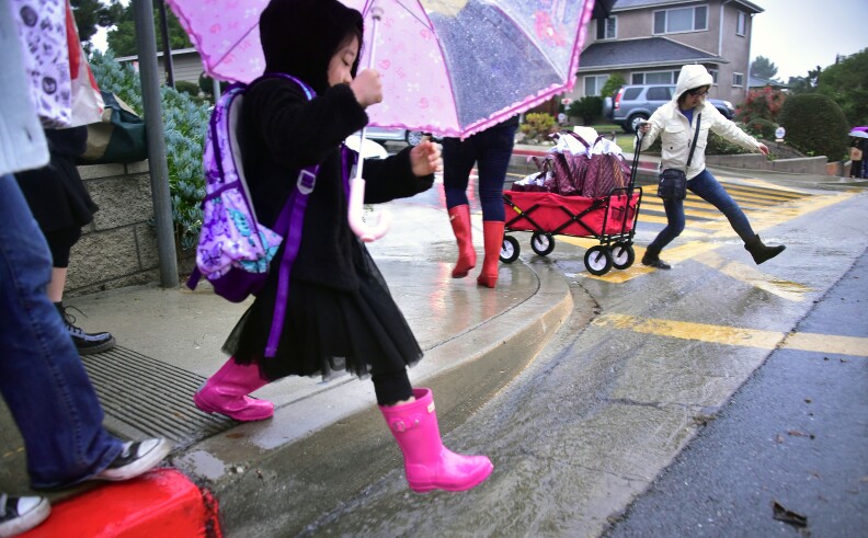 Students and parents walk on the way to school in the rain on Dec. 16, 2016 in Monterey Park as the biggest rain storm of the season hits Southern California.