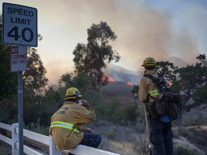 Firefighters watch as a brushfire threatens homes in the unincorporated Newbury Park neighborhood west of Thousand Oaks in Ventura County.