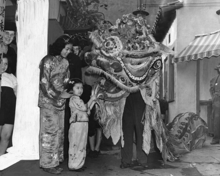 A women and girl pose with a person in a Chinese dragon costume