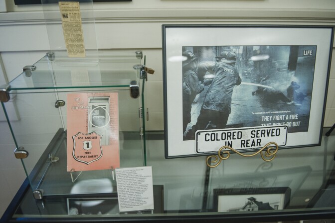A book with a photo of a "white adults" sign that kept black firefighters from eating meals with their white colleagues in a Los Angeles firehouse after integration, and iconic photographs of civil rights protestors being sprayed with fire hoses are displayed at the African American Firefighter Museum in Los Angeles, California.