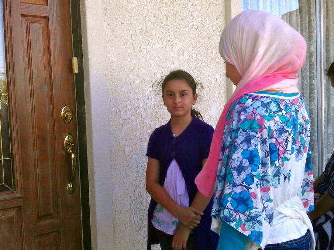 Linna and her sister wait for a neighbor to open the door.