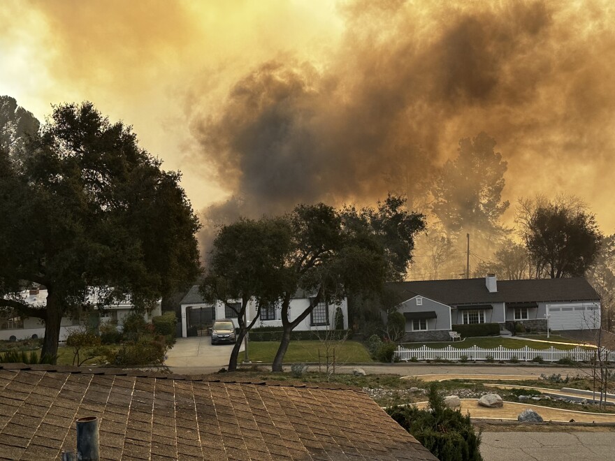 Dark smoke rises behind two homes