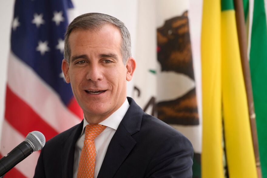 Mayor Eric Garcetti speaks at a news conference. In the background is the Los Angeles county logo.