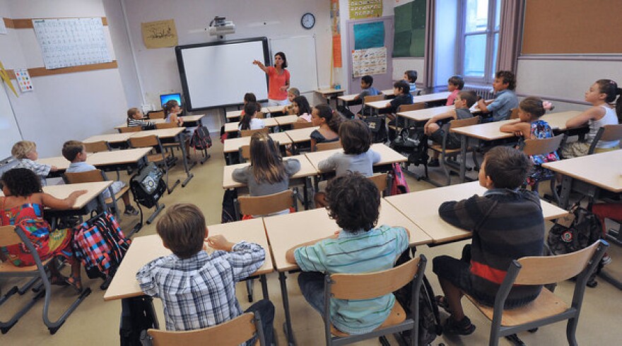 A teacher welcomes pupils in a classroom at David Johnston primary school on September 4, 2012.