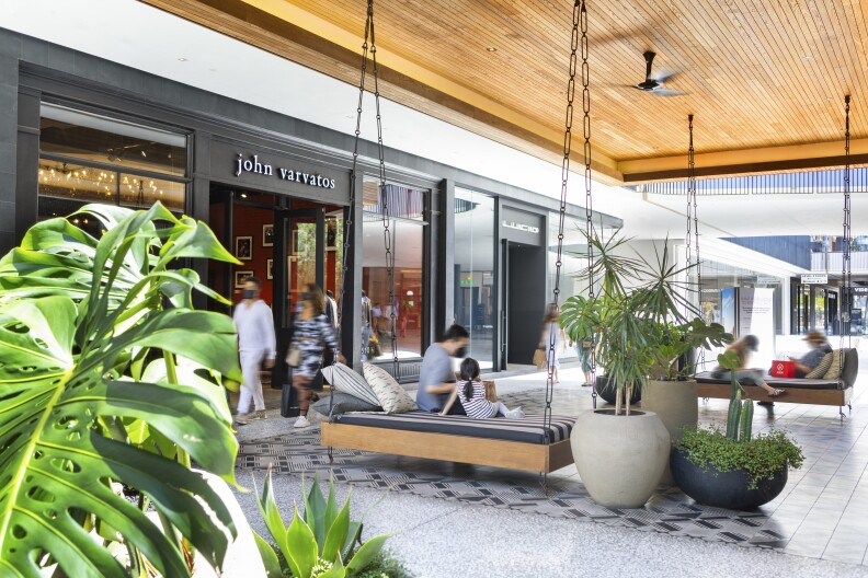 Westfield shopping center Interior. A man and a young girl sit on a suspended bench.
