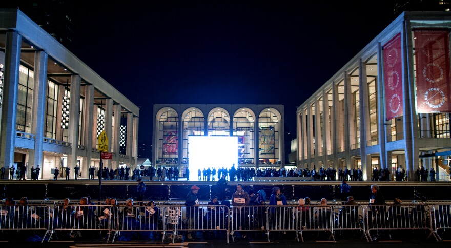 People, some in wheelchairs, gather at Lincoln Center, with the Metropolitan Opera House in the background, as they protest "The Death of Klinghoffer."