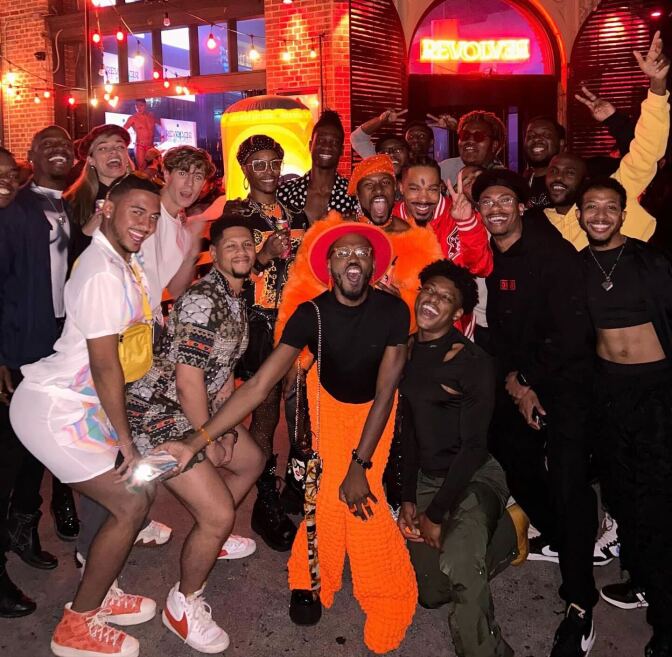 A group of people of various shades of brown pose for a photo at a party. 