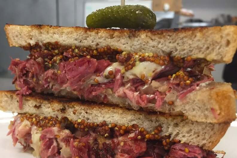 A pastrami sandwich cut in half, the cross-section facing the camera.