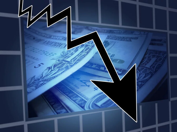 A photo illustration features a black arrow pointing downwards towards the right-hand corner of the blue-tinted image, superimposed over a pile of dollar bills. 