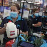 MIAMI, FLORIDA - APRIL 13: Lay Guzman stands behind a partial protective plastic screen and wears a mask and gloves as she works as a cashier at the Presidente Supermarket on April 13, 2020 in Miami, Florida. The employees at Presidente Supermarket, like the rest of America's grocery store workers, are on the front lines of the coronavirus pandemic, helping to keep the nation's residents fed. (Photo by Joe Raedle/Getty Images)
