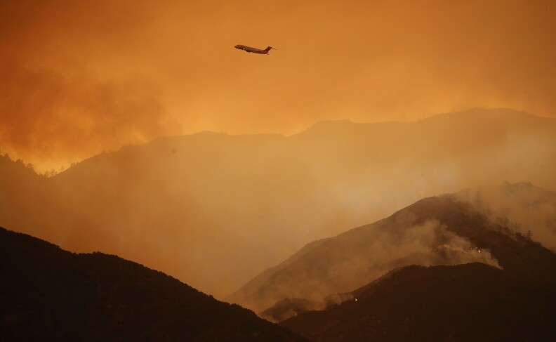 CORONA, CA - AUGUST 08:  A firefighting airplane flies above the Holy Fire as it burns in Cleveland National Forest on August 8, 2018 in Corona, California. The fire has burned at least 6,200 acres and destroyed twelve structures.  (Photo by Mario Tama/Getty Images)